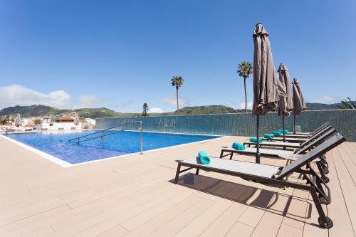 拉拉古纳拉古纳大酒店的游泳池旁一排带遮阳伞的椅子