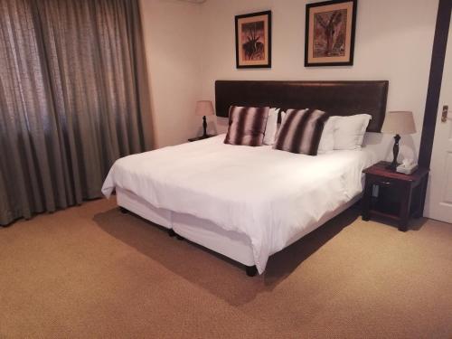 金伯利Kalahari Lodge Kimberley的卧室配有一张带白色床单和枕头的大床。