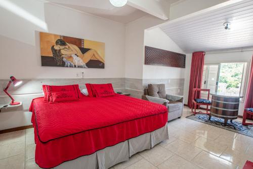 本图贡萨尔维斯卡萨塔斯卡旅馆的一间卧室配有红色的床和椅子