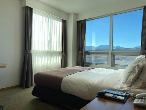 束草市马瑞蒙斯酒店的一间卧室设有一张床和一个大窗户
