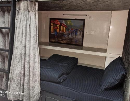乌代浦Dormitory的配有窗帘和电视的客房内的一张床位
