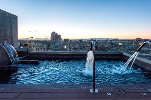 马德里Gran View Apartments的一座带瀑布的建筑屋顶上的游泳池