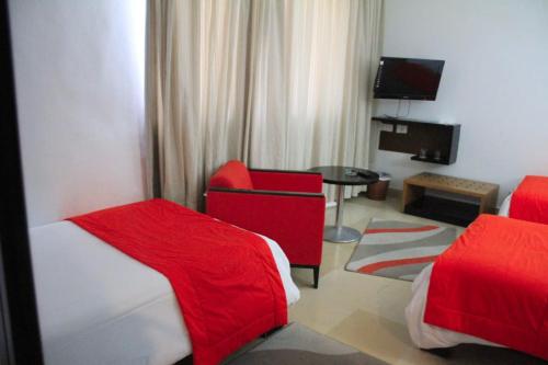 突尼斯hôtel LE PACHA的酒店客房,设有两张床和一张红色椅子