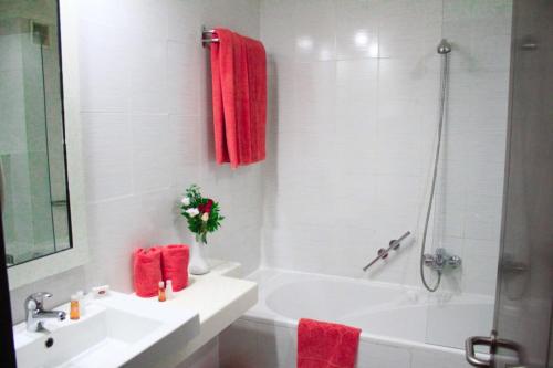 突尼斯hôtel LE PACHA的浴室设有水槽、浴缸和红色毛巾。