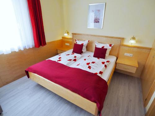 圣卡尼兹凯瑟琳旅馆的一间卧室配有一张大床,配有红色床单和红色枕头