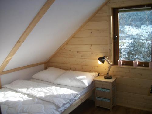 克雷尼察Domek Stokrotka的木制客房的一张床位,设有窗户