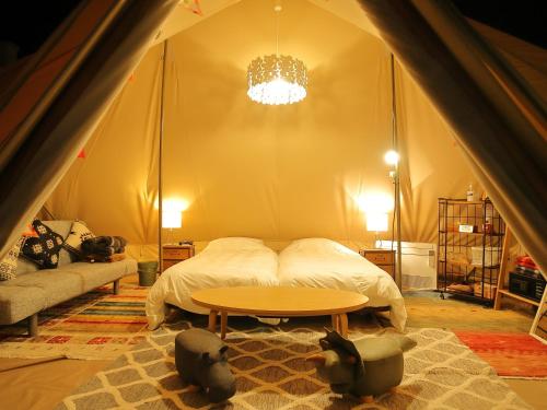 IchikikushikinoFukiagehama Field Hotel的一间卧室配有一张床,帐篷内配有一张桌子