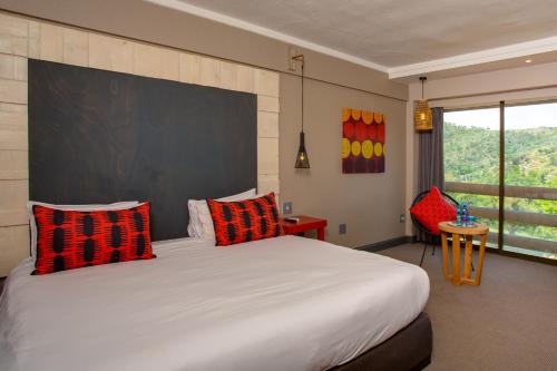穆德斯蒂夫26° South Bush Boho Hotel的一间卧室配有一张大床,提供红色和黑色的枕头