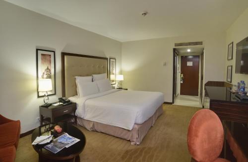 卡拉奇卡拉奇明珠大陆酒店的酒店客房带一张大床和一把椅子