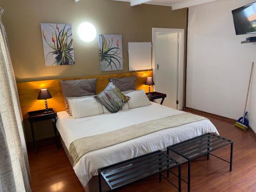 香槟谷Little Acres Drakensberg Accommodation的一间卧室配有一张带两盏灯的大型白色床。