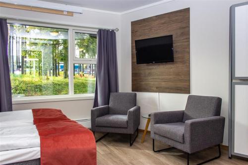 希恩Hotell Fritidsparken的一间带两把椅子和一张床的卧室以及一台电视