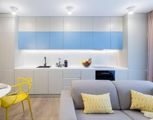 沃伦塔里Il Lago - Azur - Cozy Luxurious Smart Home By The Lake的带沙发的客厅和带蓝色橱柜的厨房。