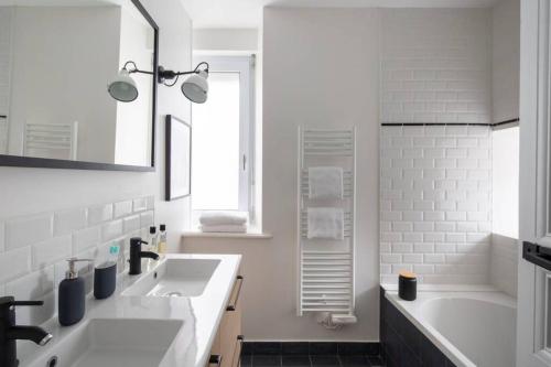 迪纳尔Dinard, très bel appartement***** avec vue sur mer的白色的浴室设有2个盥洗盆和1个浴缸。