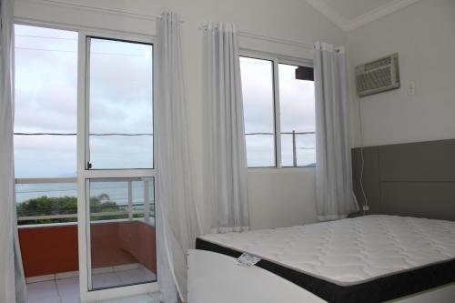 邦比尼亚斯Praia de Quatro Ilhas a 50 metros do mar的一间卧室设有一张床和两个大窗户