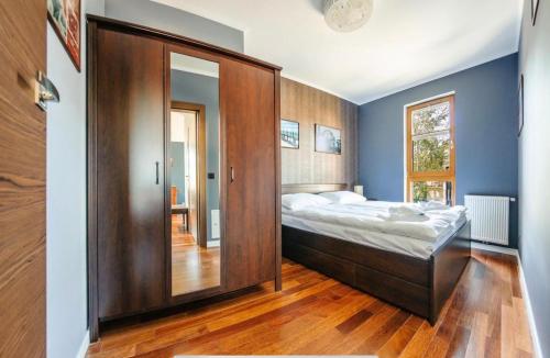 索波特Urus Home Sopot的一间卧室配有一张大床和一个木制橱柜