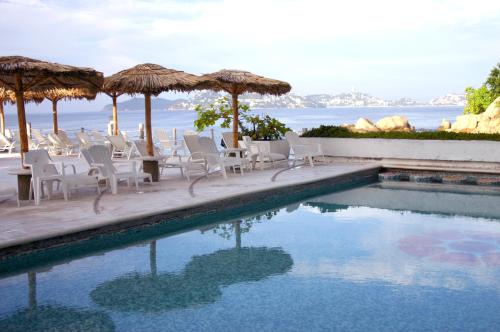 阿卡普尔科Hotel Las Torres Gemelas Acapulco的毗邻大海的带椅子和遮阳伞的游泳池