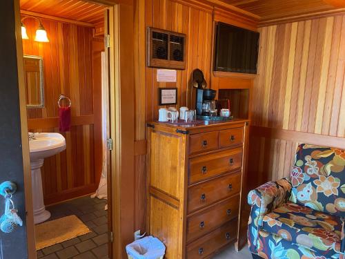 林肯市Whistling Winds Motel的一间位于客房内的带梳妆台和椅子的浴室