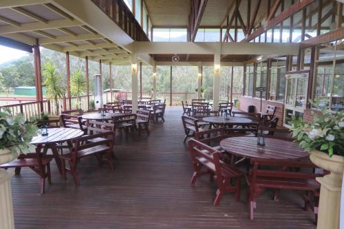霍尔斯加普Halls Gap Valley Lodges的餐厅设有木桌、椅子和窗户。