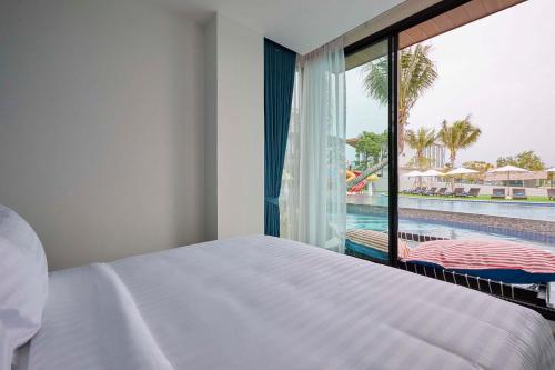 七岩Elmas Cha Am Design Hotel的一间卧室配有一张床,享有游泳池的景色