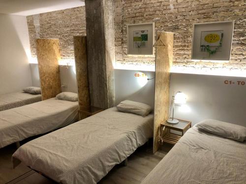 瓦伦西亚Art&Flats Hostel的带三张床和砖墙的房间