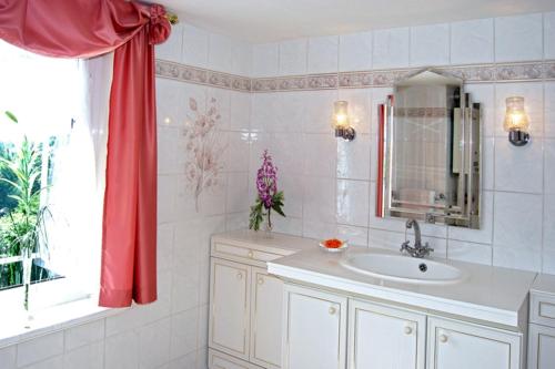 马瑟尔贝格Panoramaferienwohnung Bergwiese的一间带水槽和红色窗帘的浴室