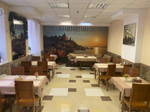 尼古拉耶夫卡拉维拉酒店的餐厅设有桌椅,墙上挂有绘画作品
