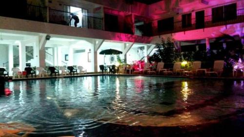 梅尔加Hotel Cacique Guaicani的游泳池,酒店内设有粉红色的灯光