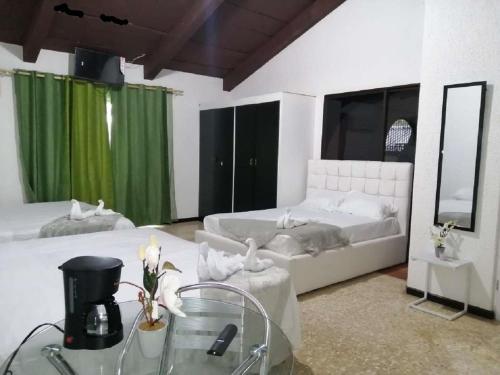 PotrerillosCasona del Valle的一间卧室配有两张带绿窗帘和玻璃桌的床