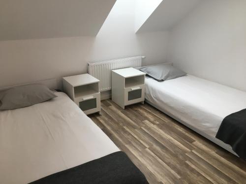 热舒夫apartament的配有白色墙壁和木地板的客房内的两张床