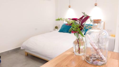 阿什杜德Primrose Boutique Apartment的一间卧室配有一张床和一张带花瓶的桌子