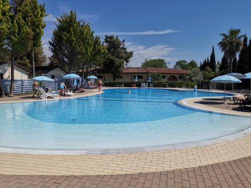 维亚雷焦Mobile home comfort Viareggio - Camping Paradiso - R008的一个大型蓝色游泳池,周围的人坐在游泳池周围