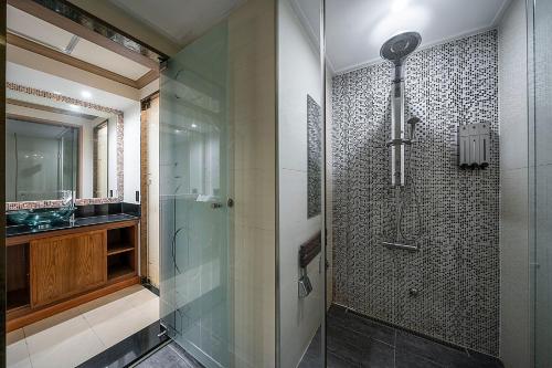 龙仁市龙仁天玺酒店的一间带玻璃淋浴和水槽的浴室