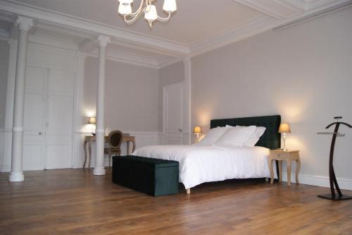 BrinayGite la chaumière Le chateau de la Brosse的白色卧室配有一张大床和吊灯