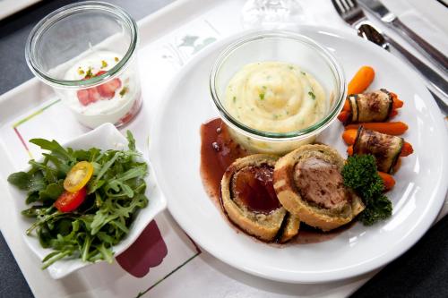 科隆科隆道依茨青年旅馆的盘子里放有肉和蔬菜的盘子