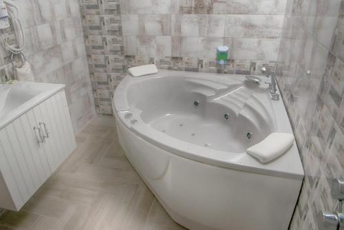 西格伏沙尔克甜蜜生活家庭旅馆的浴室设有白色浴缸,铺着瓷砖。