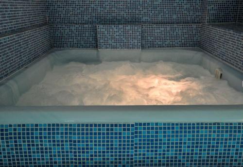 沃伊内亚萨Zan Hotel的瓷砖客房内的热水浴池装满雪