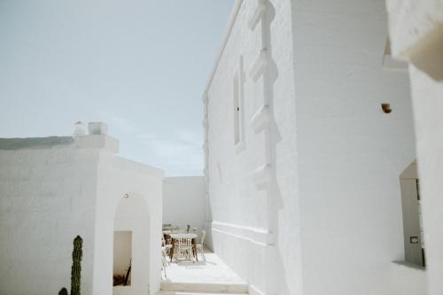 莫诺波利Masseria D'Erchia的白色的客房设有桌子和白色的墙壁