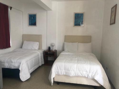 RotaCoral Garden Hotel的配有白色床单的客房内的两张床