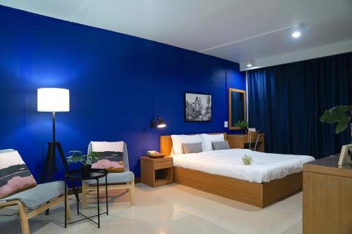 曼谷The View Residence的蓝色卧室,配有床和两把椅子