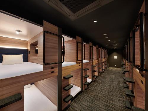 东京Smart Stay SHIZUKU Shinagawa-Oimachi的客房设有许多双层床和木墙。
