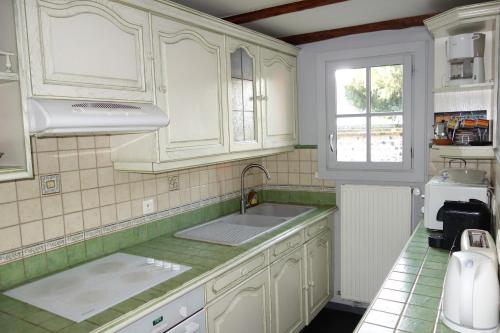 翁弗勒尔Boudin Cottage Honfleur的厨房配有白色橱柜、水槽和窗户。