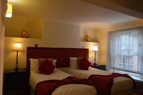 博克斯本森之家博克斯酒店的一间卧室设有两张床、两盏灯和一个窗户。