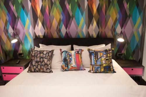 南安普敦Village Hotel Southampton Eastleigh的一间卧室配有带枕头的床和色彩缤纷的墙壁