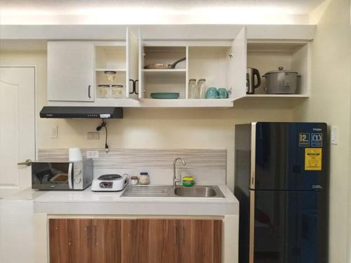 卡加盐德奥罗One Oasis By Paseo de Corazon Residence的厨房配有白色橱柜和黑色冰箱。