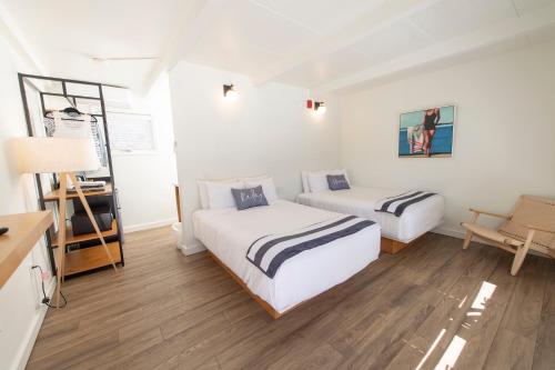 韦尔弗利特Endless Coast, A Boutique Hotel的配有白色墙壁和木地板的客房内的两张床