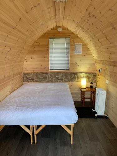 HullandPoplars Farm Site Glamping Pods的木制客房内的一间卧室配有一张大床