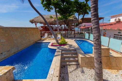 圣玛尔塔GIO Hotel Tama Santa Marta的一座棕榈树游泳池,位于大楼旁
