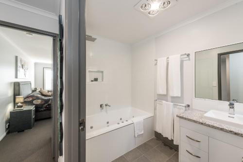 土乌巴雅典娜汽车旅馆的白色的浴室设有浴缸和水槽。