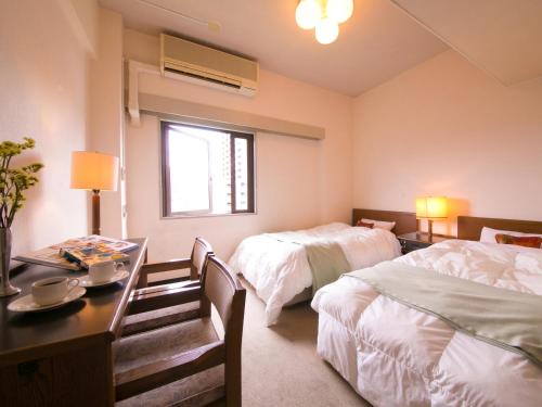 静冈ホテル盛松館的酒店客房设有两张床、一张桌子和一张书桌。