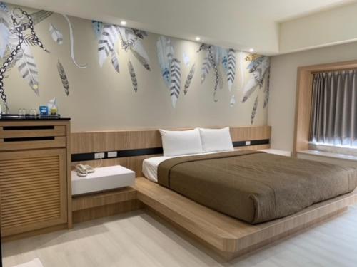 台南永华春休闲商务旅馆的一间卧室配有一张床和一堵带羽毛的墙